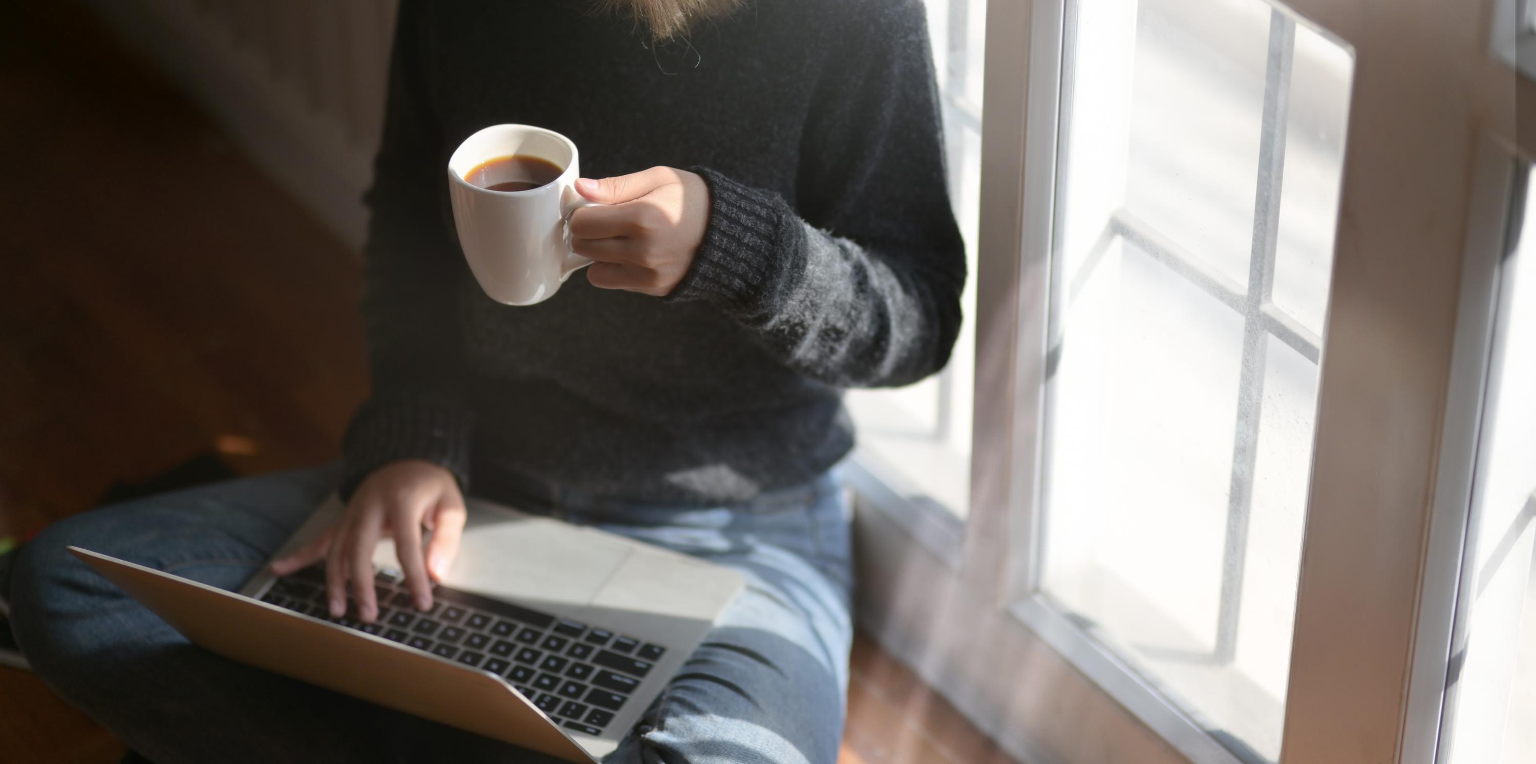 woman using laptop drinking coffee