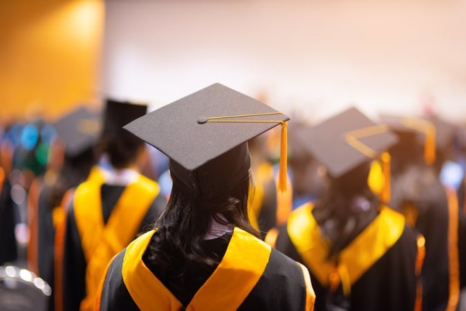 A crowd of tudents standing in grad gowns at graduation ceremony