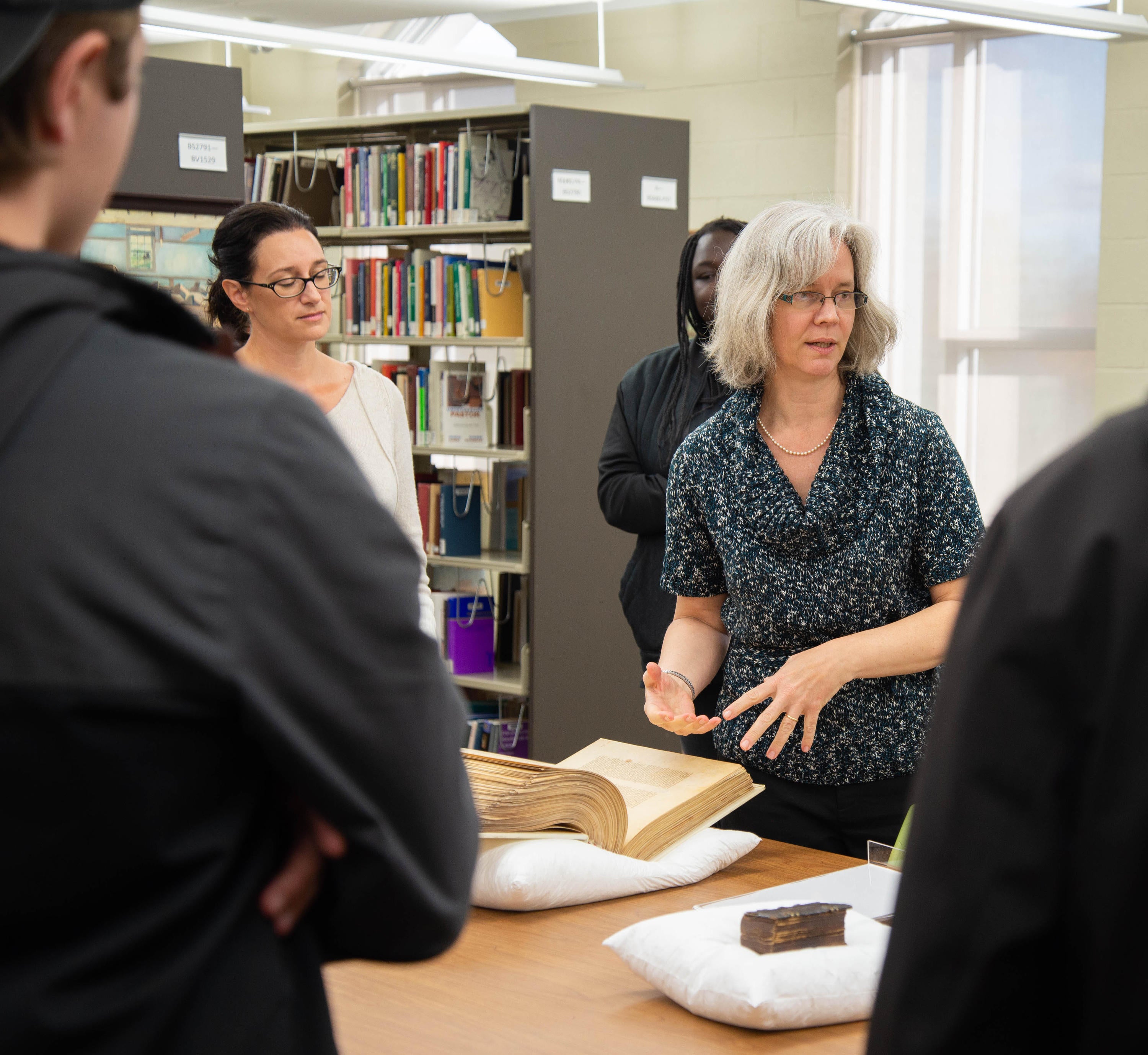 Archivist-Librarian Laureen Harder-Gissing illustrates the history of book technology with a large 13th-century manuscript Bible and tiny 17th-century printed Dutch hymnal.