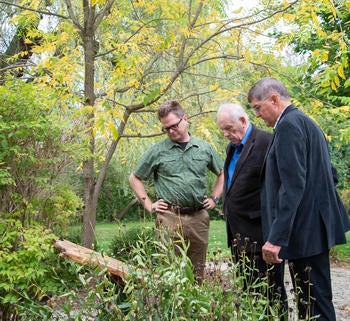 Marcus Shantz, John Ruth, and Wilmer Martin ponder the revised plaque in Grebel's Swiss Mennonite Heritage Garden.