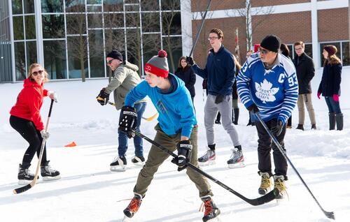 Staff and faculty vs students hockey game on student-built rink