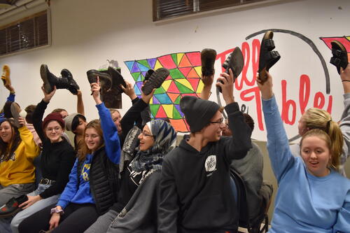 Students raise shoes in the air during a room mate game