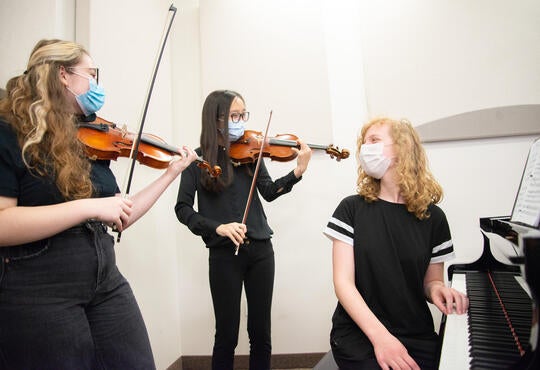Two violinist and a pianist students play music together