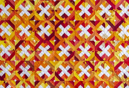 the quilt created by Grebel staf, faculty, students, and visitors. Orange, red, yellow, and white colour scheme