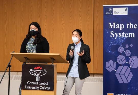 Two students speaking at microphone on stage during Map The System Competition