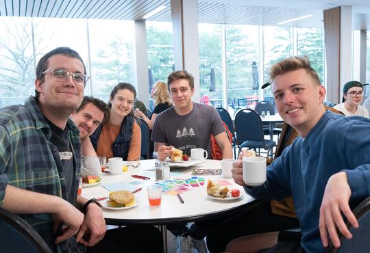 Students sitting at table in Grebel dining room eating breakfast