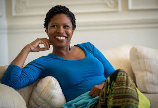 Dr. Johonna McCants-Turner sits for a photo, smiling on a couch
