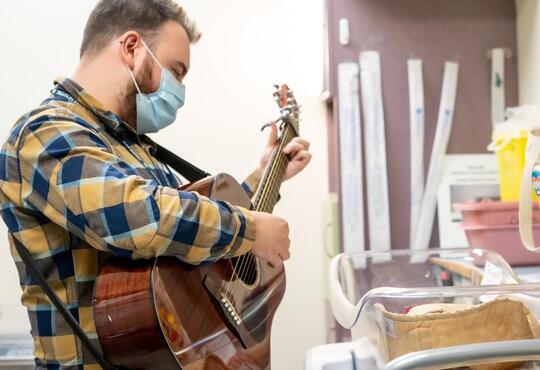 Tyler Reidy playing guitar in hospital room