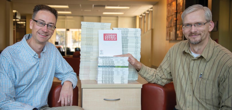 Jeremy Bergen (CGR editor 2010-2017) and Derek Suderman (current CGR editor) with stack of all published CGR issues.