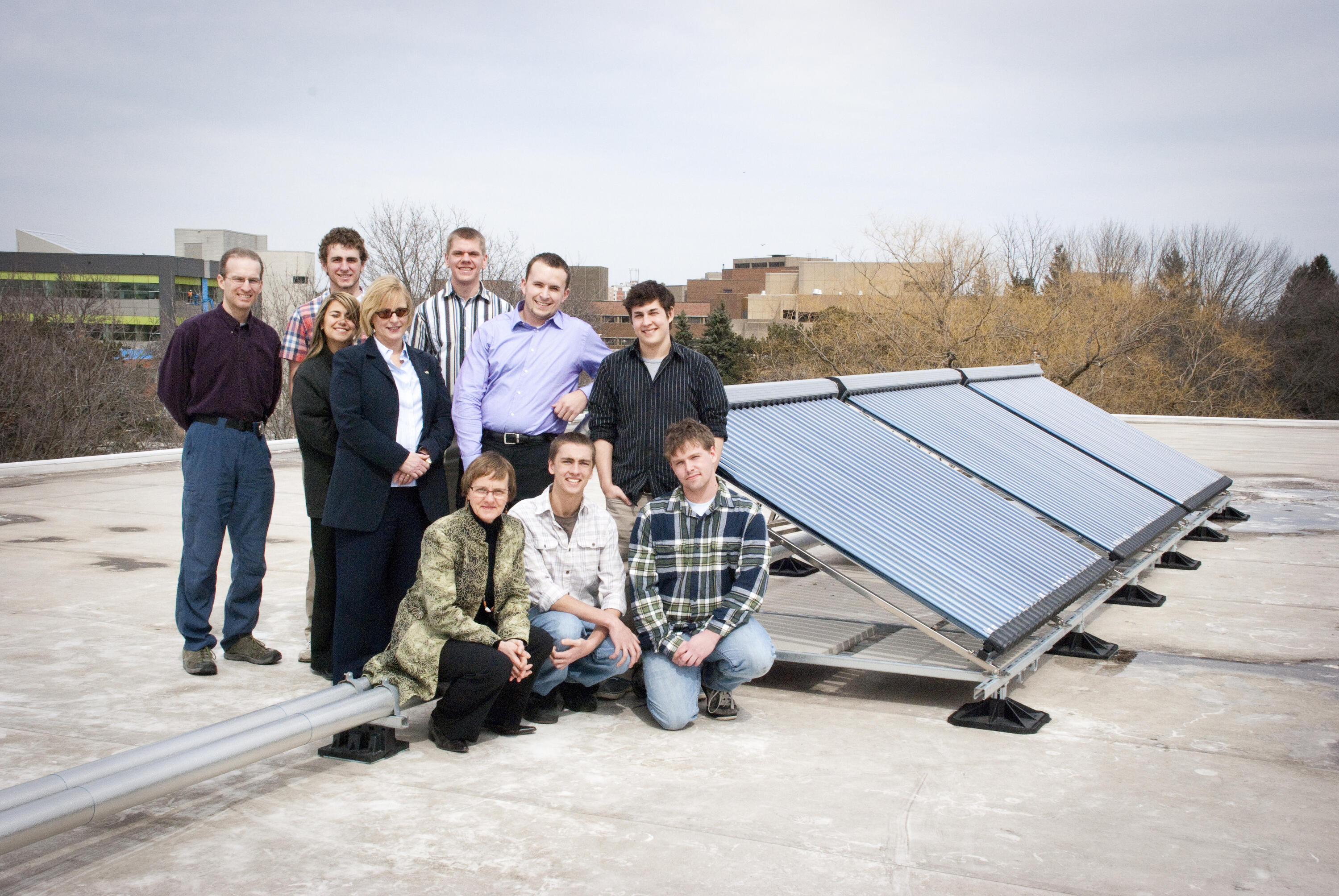 Solar grebel team beside solar panels on grebel roof