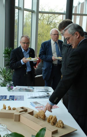 Henry Paetkau points out details of the building to Ken Coates, while David Perrin and Glenn Cartwright look on