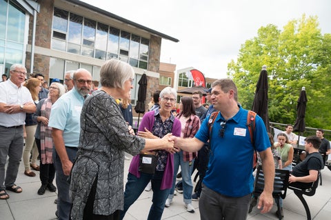 two grebel alumni greet eachother cheerfully on the patio outisde