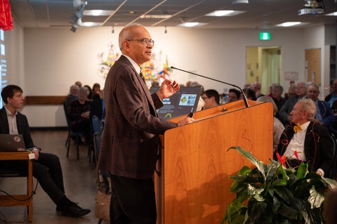 Vivek Goel speaking at podium in Grebel Cafeteria
