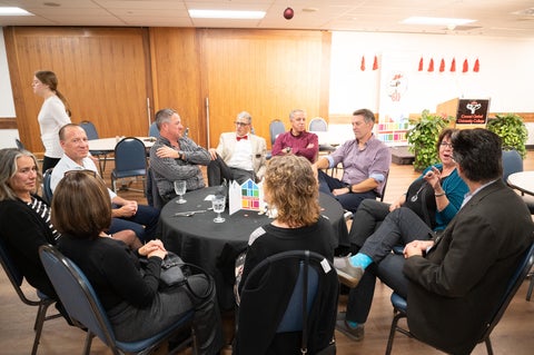 alumni gathered around a table with a black tablecloth 