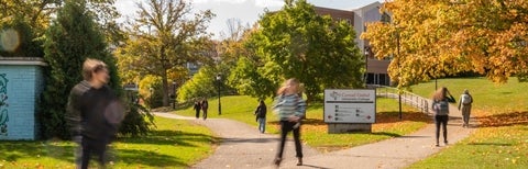 A Fall view of grebel, from a path leading to campus. Students walk bristly by.