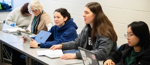 5 students in a classroom, sitting in a row