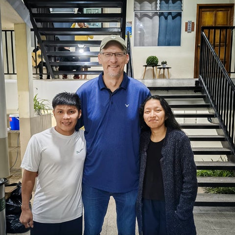 Derek Suderman posing with two students