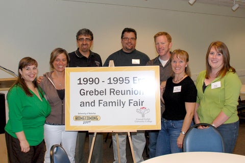 Reunion committee stands with a sign for homecoming