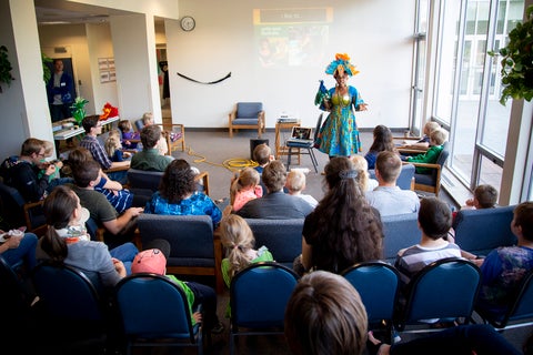 Nadia L. Hohn, in a bright costume, performs for families at a reunion