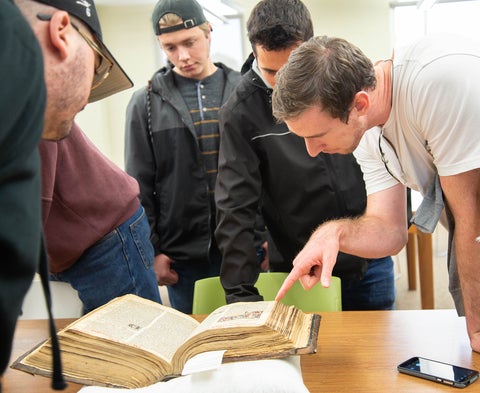 History class looking at an old book in the Mennonite Archives of Ontario