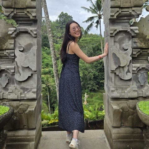 Tiffany stands between two decorative stone pillars, smiling at the camera