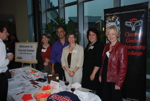 grebel alumni stand behind a table of swag from the 80's era