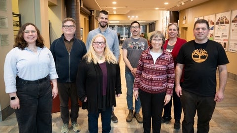 Eight members of the committee stand in the atrium together for a group photo