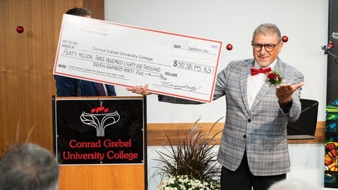 Fred martin holds up a novelty cheque with the total amount he has helped raise during his career at Grebel