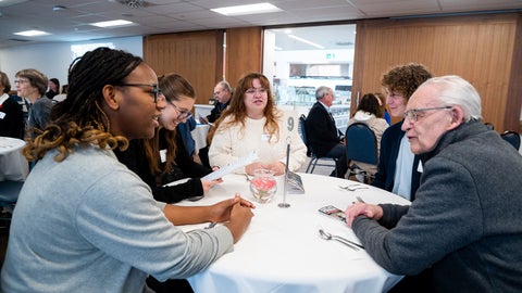 Students visiting around a table with a donor
