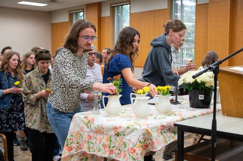 three people placing fresh flowers in vases during a chapel service