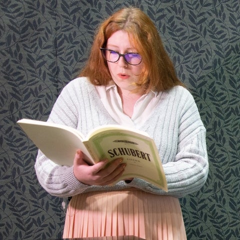 ashley Johnson holding sheet music book 