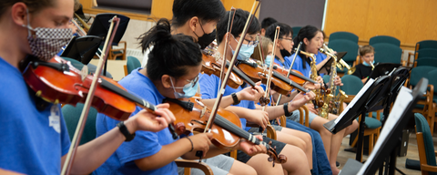 ommc participants play violins in orchestra