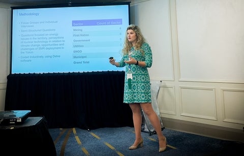 Cole Atlin speaking in front of a projection screen 