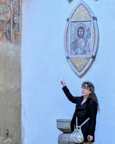 Colleen Shantz pointing to an artowork on the wall above her depicting Jesus
