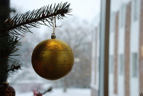 A golden Christmas ornament hanging on Christmas tree 
