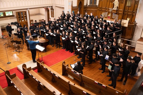 a large group of choral singers sing in a church
