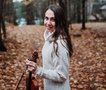 Emily Yarascavitch holding a violin in the woods
