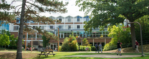 a view of the Grebel residence wing, through the trees on a summer day