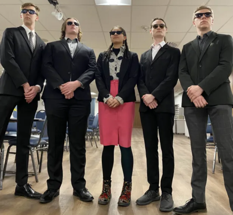 5 students in suits wearing sunglasses in a serious pose