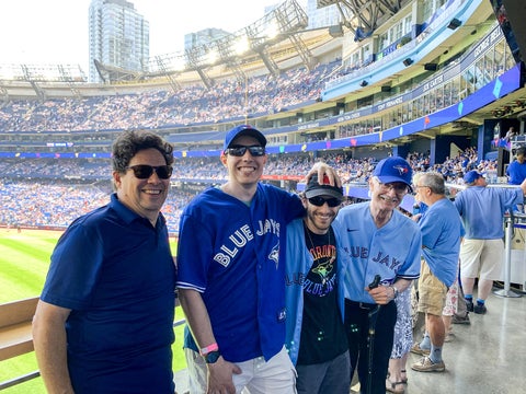 alumni dressed in bluejays merch in the stands at a bluejays game 