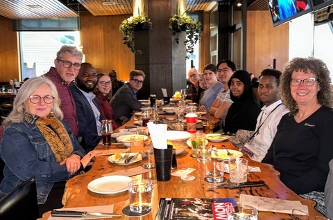 alumni gathered on both sides of a table with plates of food