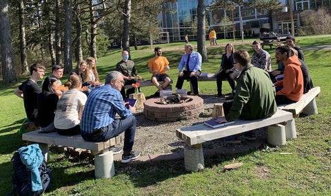 students, staff and faculty gathered around fire pit 