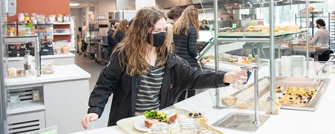 Grebel student loading plate in self-serve area of kitchen