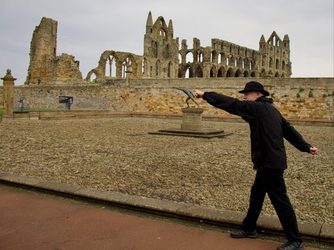 Len Friessen mimics the pose of a sculpture in a historic stone built castle-esque setting