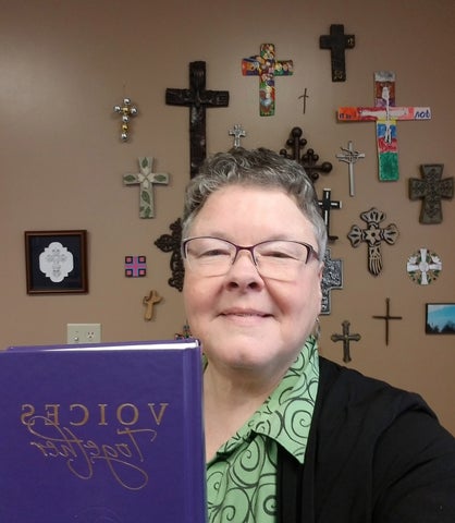 louise wideman holding voices together book standing in fornt of a wall full of crosses