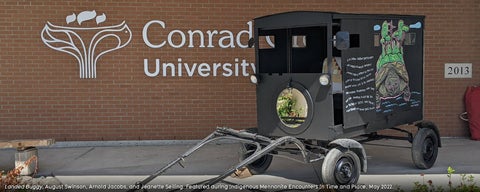 A black horse drawn buggy sits out front of the college, with indigenous art depicting Turtle Island