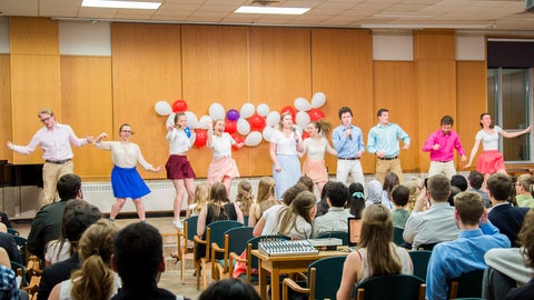 Students dressed in white and red dance on on the stage in the great hall during a talent show