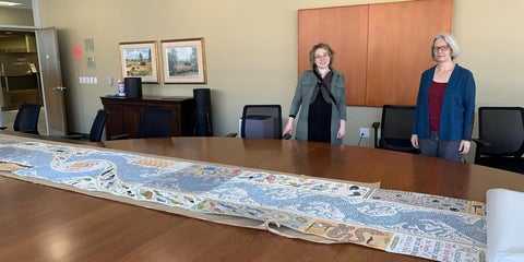 two people standing by a 20-foot long scroll artwork