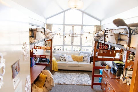 A bright Grebel residence room with sun streaming through window beside tidy bunk beds