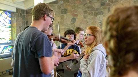 People in conversation and playing a violin and a guitar